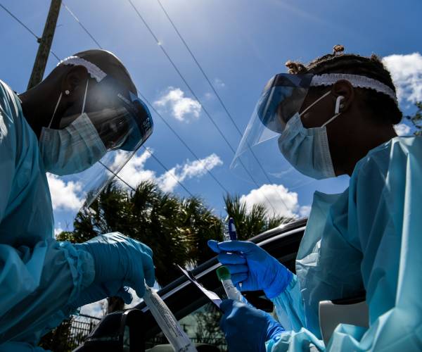 two medical personnel in surgical garb and protective face masks