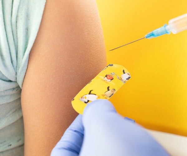 closeup of a child's arm, getting shot, band-aid with cartoon characters