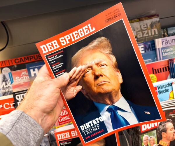 a hand holding a magazine with a cover photo of donald trump saluting and dictator trump as the headline