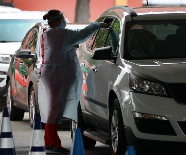 a health care worker swabs a person in a white 