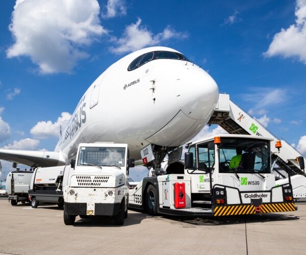 New modern Airbus A350 XWB passenger jet plane about to be towed by an airport towing vehicle.
