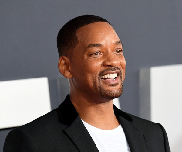 will smith stands on red carpet