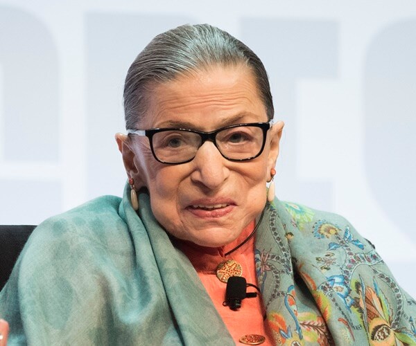 justice ruth bader ginsburg sits in a chair on a stage a speaks
