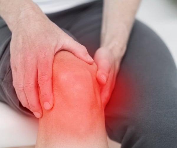 person holding knee that is highlighted in red to show pain