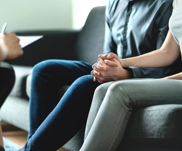 a man and woman going to therapy with a doctor writing notes