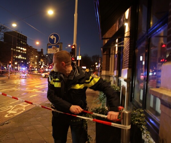 A Dutch police officer puts tape to close the street near the hostage situation in the Apple store