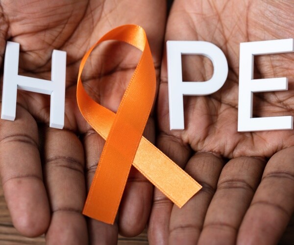 two hands holding a ribbon that symbolizes leukemia and a the word 'hope'