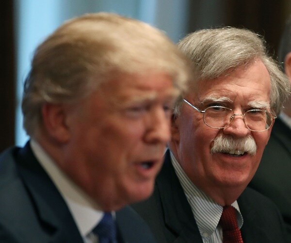 john bolton looks over at president donald trump in the foreground
