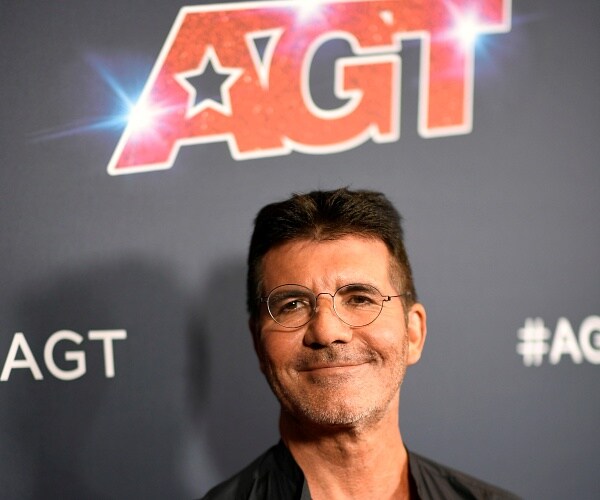 simon cowell stands on red carpet