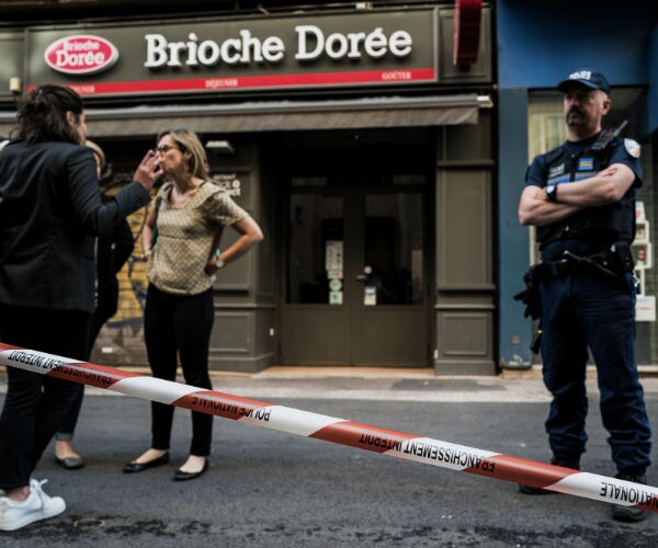 two women and a police officer stand near crime tape near the blast site