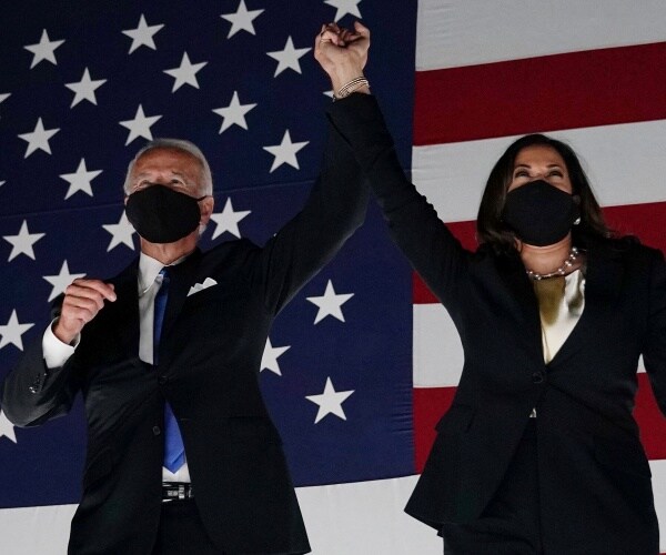 biden and harris hold hands and wear face masks