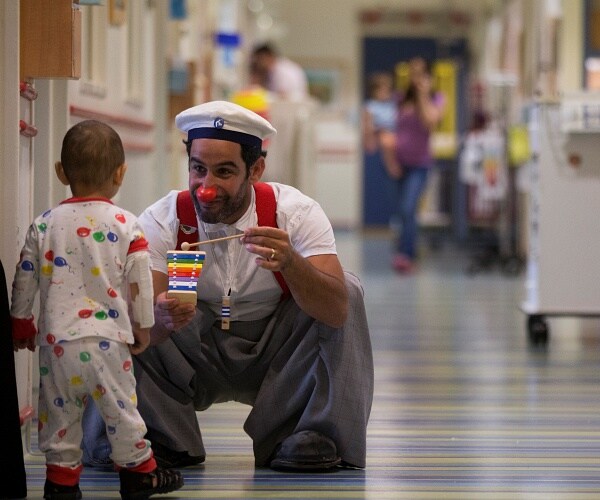 child and clown in hospital hallway