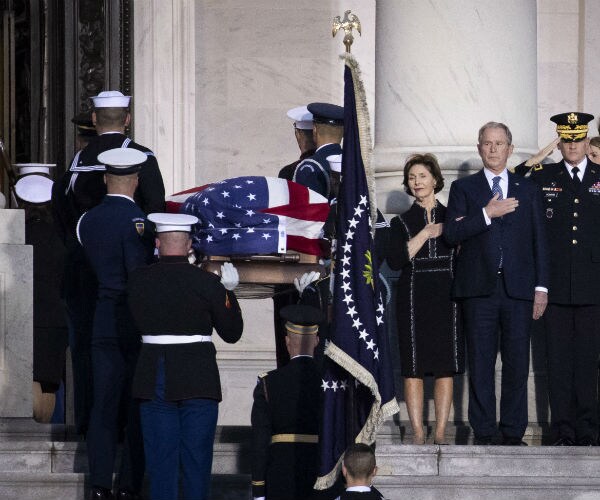 bush's flag-draped casket is brought into the capital as george w. Bush salutes
