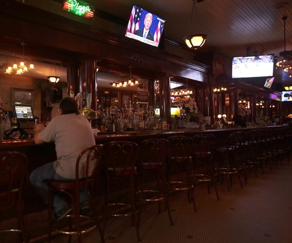 a single man sits at an empty bar