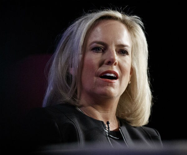 kirstjen nielsen speaks before a crowd on a dark stage