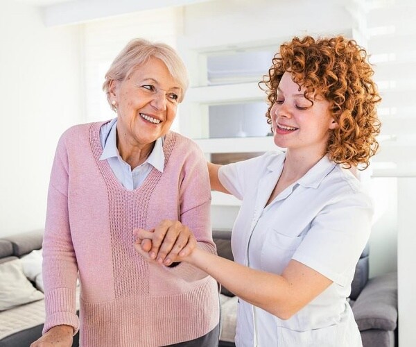 a nurse helping an older woman to walk