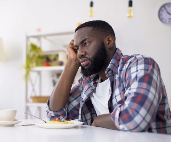 man sitting at his dining table for breakfast, looking straight ahead, depressed, not eating