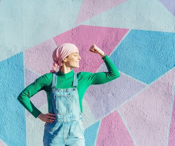 woman with scarf on head flexing arm in success