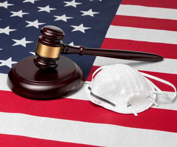 a face mask and judge gavel on an american flag