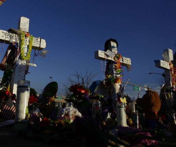 a line of white crosses decorated with wreaths and photos