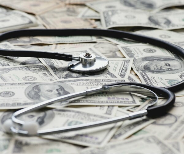 A stethscope is shown on pile of US banknotes .