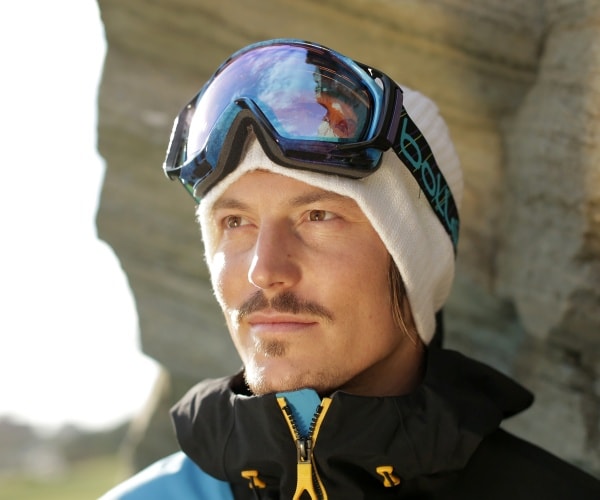 pullin in a blue and black jacket and white cap with goggles 