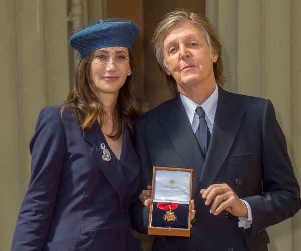 mccartney in a suit holding an award with shevell in a navy blue blazer and blue hat