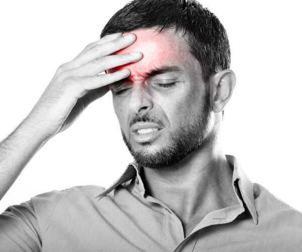 man holds head in pain, red showing where the pain is