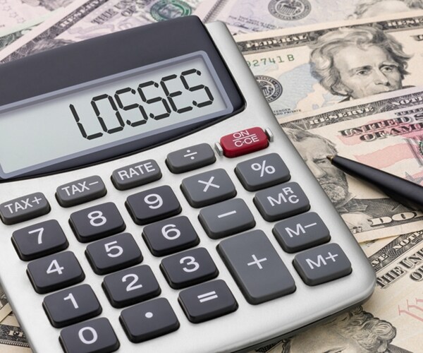 calculator with losses spelled out in display window, sitting atop various us dollar bills