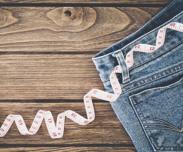blue jeans and measuring tape on wooden background