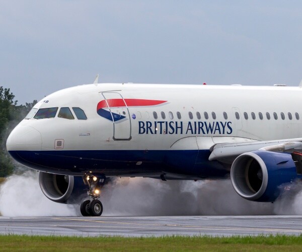  British Airways Airbus A318-112 aircraft G-EUNB landing on the wet runway with reverse thrust spraying water.