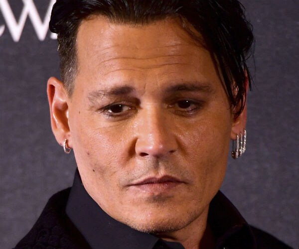 actor johnny depp is shown in black attire with several necklaces and an ear piercing