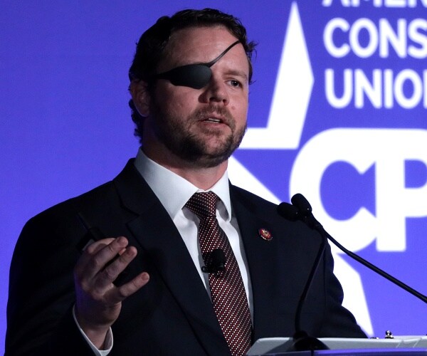 dan crenshaw stands behind podium