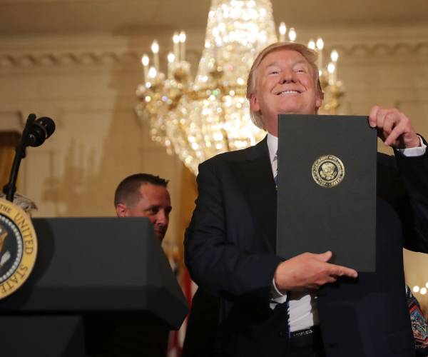 trump holding a docoment in an official folder