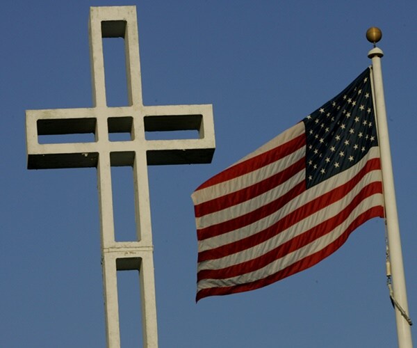 a flag flies next to a cross in the air