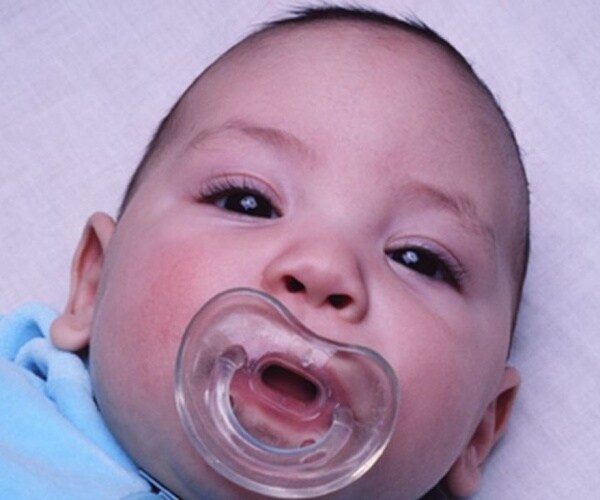 baby with pacifier in mouth looking at camera