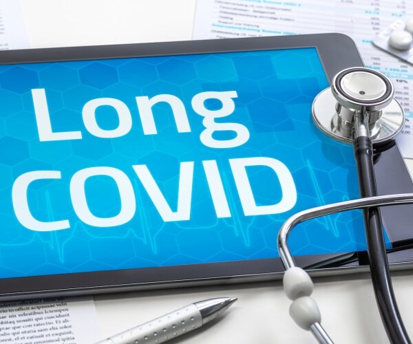 tablet with "Long COVID" on screen, stethoscope, pills