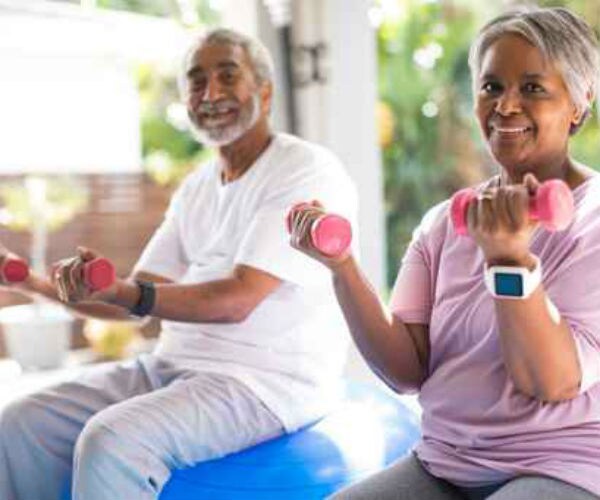 an older african american couple lifts hand weights for exercise