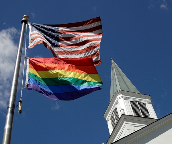 a gay pride flag flies with the american flag outside a church in kansas