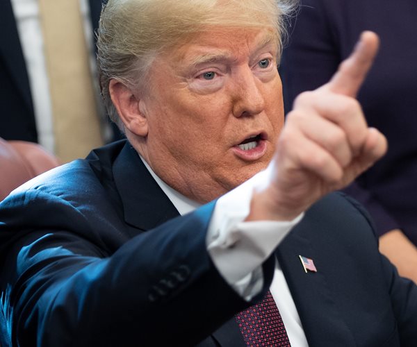 president donald trump in closeup points his right index finger upward