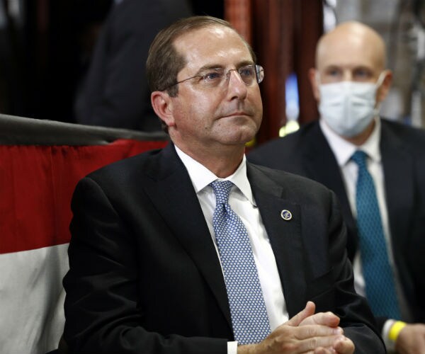 alex azar is seen in a dark suit, white dress shirt and blue and white tie