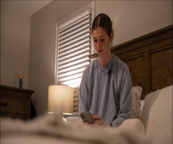 woman sitting in bed looking at sleep app on her phone