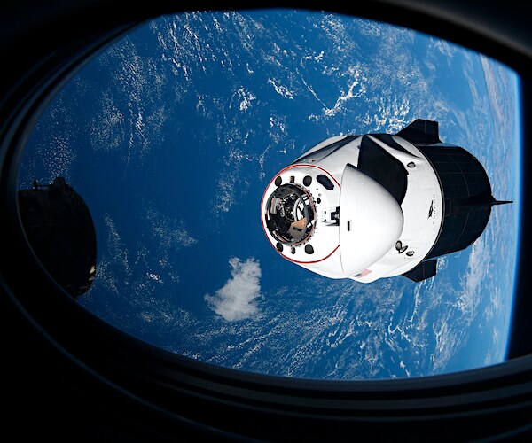 the spacex crew dragon is shown orbiting earth from the international space station