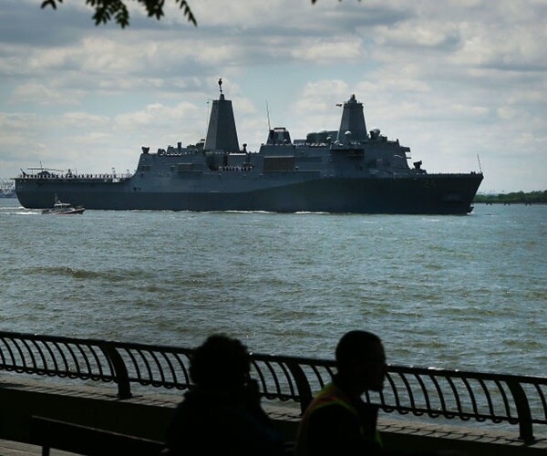 the uss arlington motors in new york harbor during fleet week while residents looks on