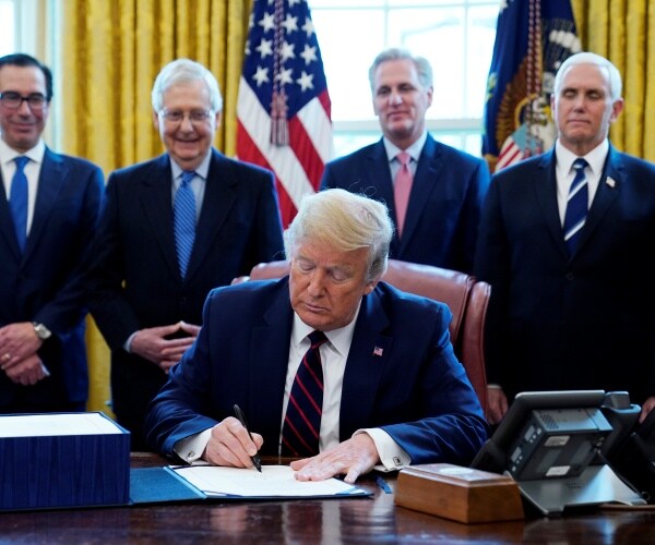 trump signing the bill with pence mcconnell mnuchin and mccarthy standing behind him