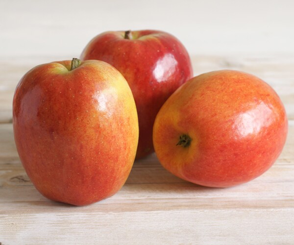 red apples sitting on a wooden board