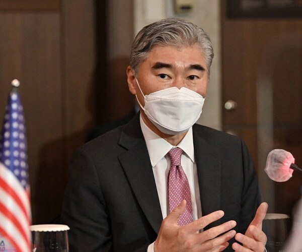 sung kim wears mask while speaking into mic