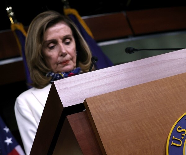 nancy pelosi stands at a podium 