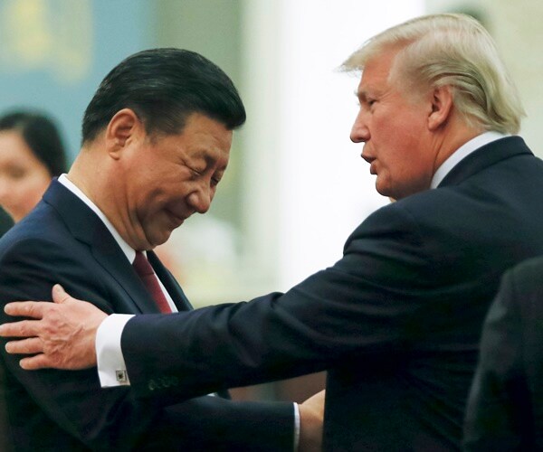 president donald trump and president xi jinping shake hands as trump puts his hand on xi's shoulder