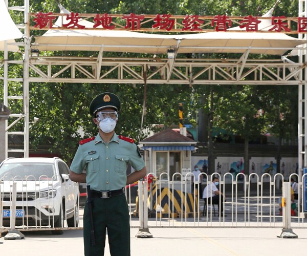 a chinese policeman stands guard outside the xinfadi wholesale market in beijing